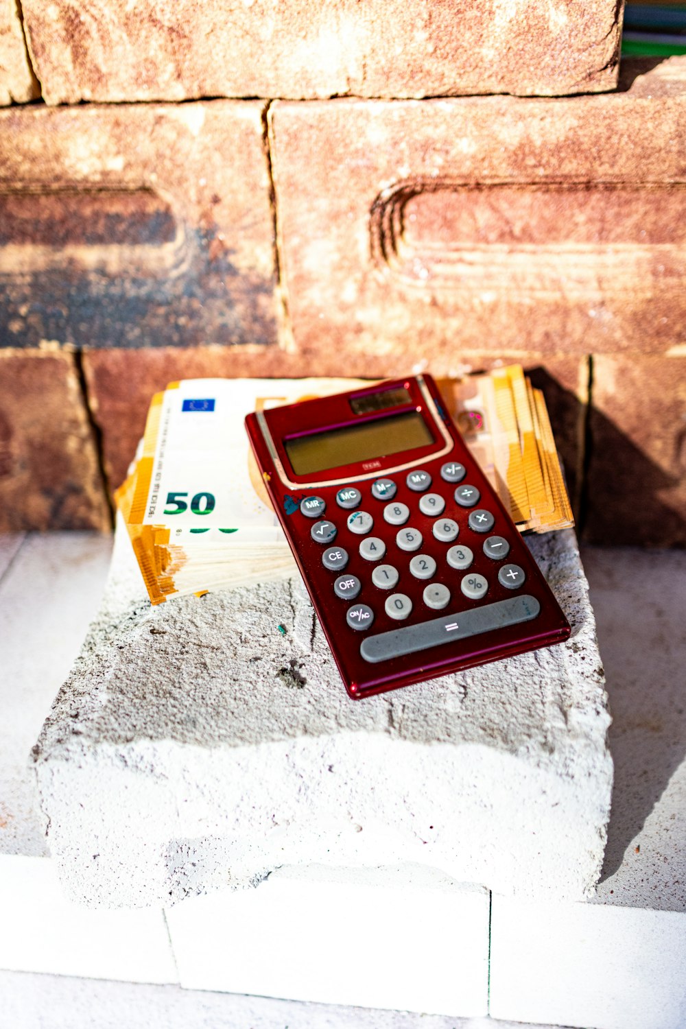 a red calculator sitting on top of a cement block