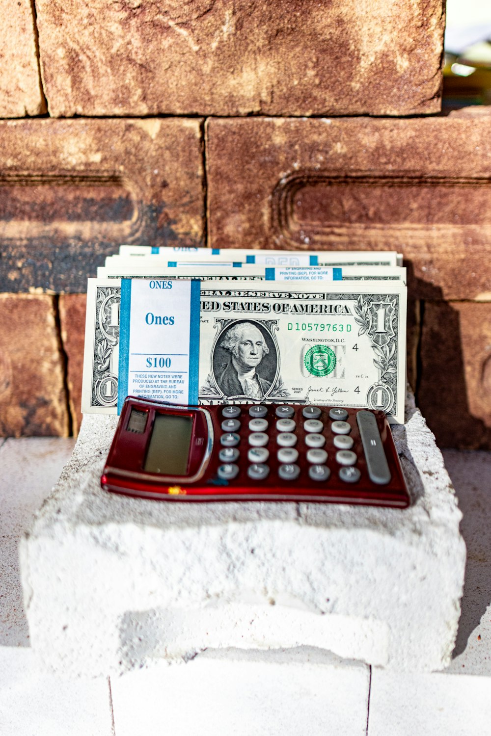 a red calculator sitting on top of a pile of money