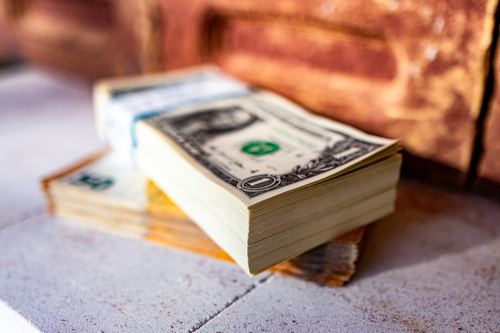 a stack of money sitting on top of a sidewalk