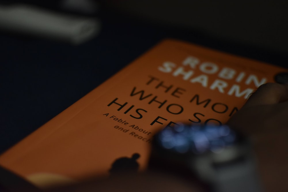 a person holding a smart phone next to a book