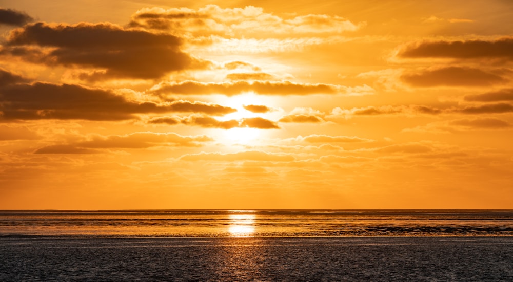 Die Sonne geht an einem bewölkten Tag über dem Meer unter