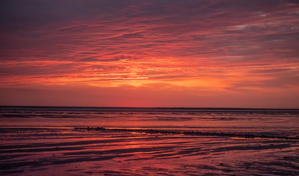 the sun is setting over the ocean on a cloudy day