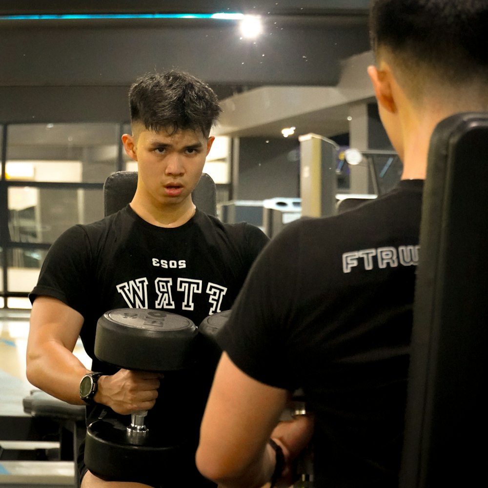 a man holding a dumbbell while standing next to another man