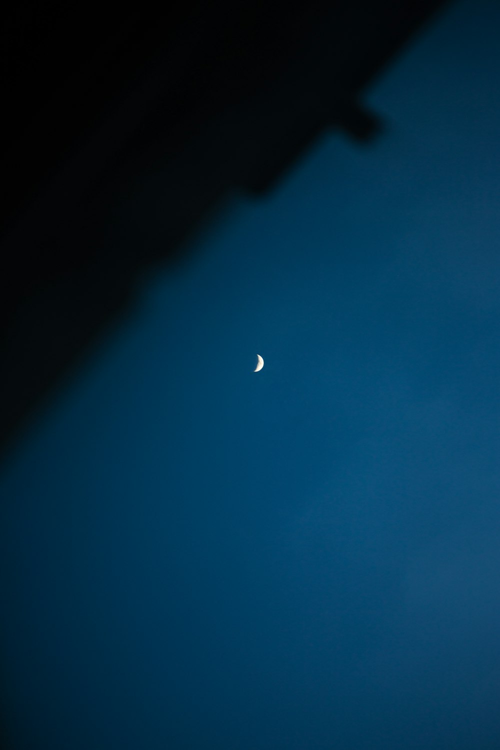 a half moon is seen in the dark blue sky