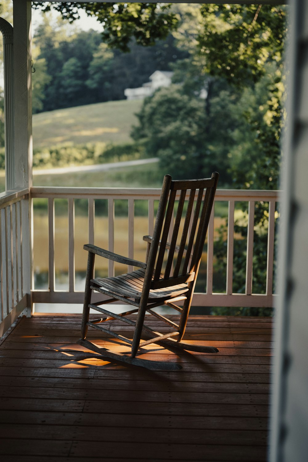 a rocking chair on a porch overlooking a field