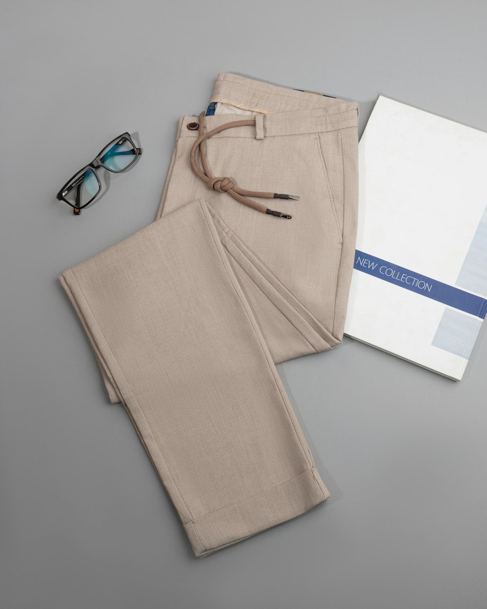 une paire de lunettes, un livre et un pantalon sur une table