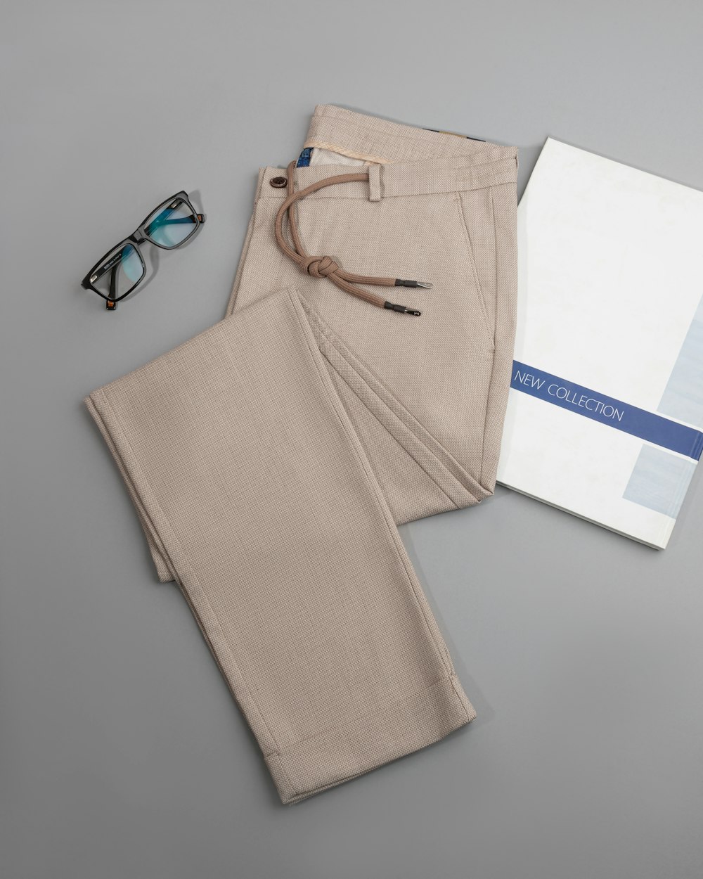 a pair of glasses, a book, and a pair of pants on a table