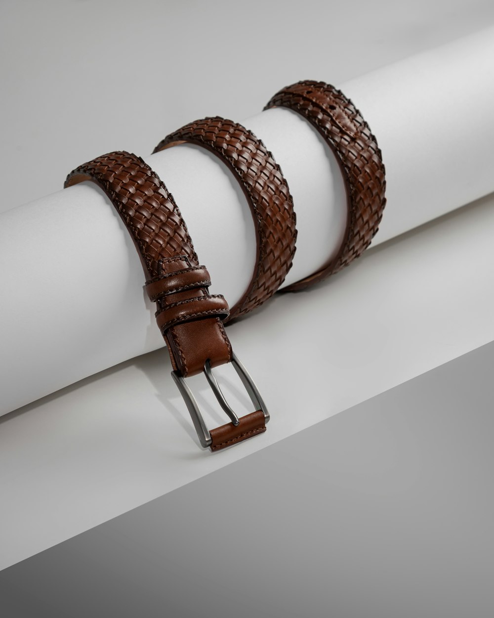 une paire de ceintures en cuir marron posées sur un morceau de papier blanc