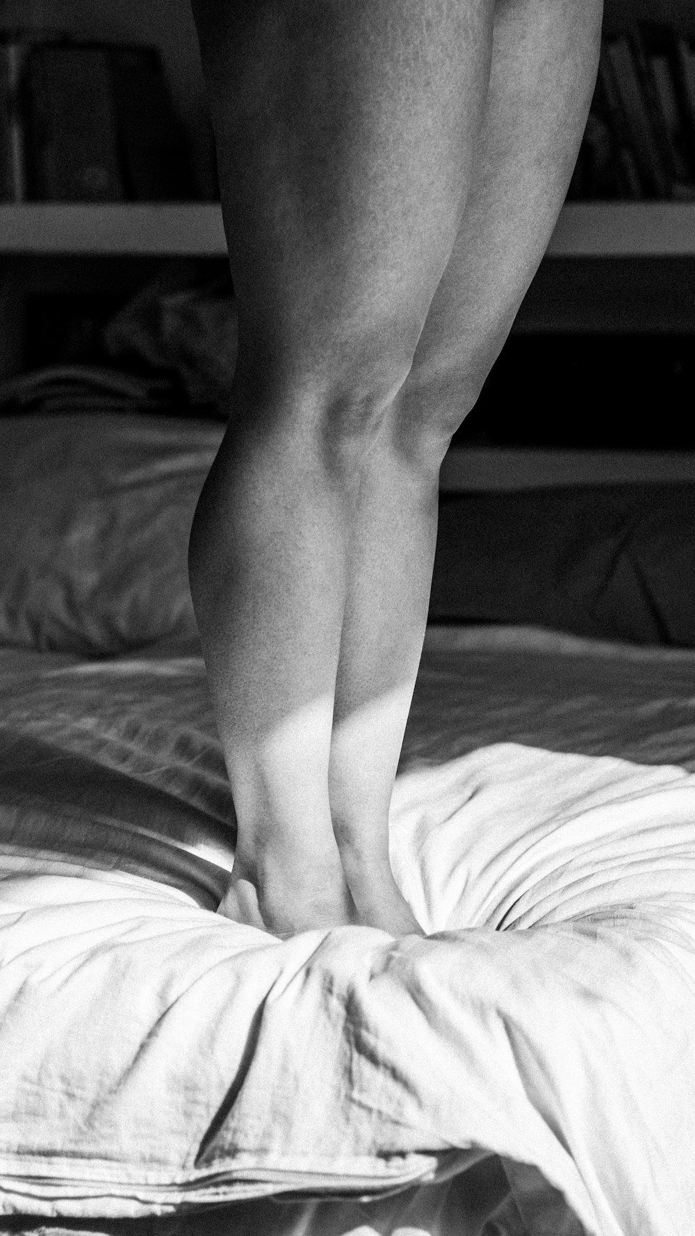 a black and white photo of a person standing on a bed