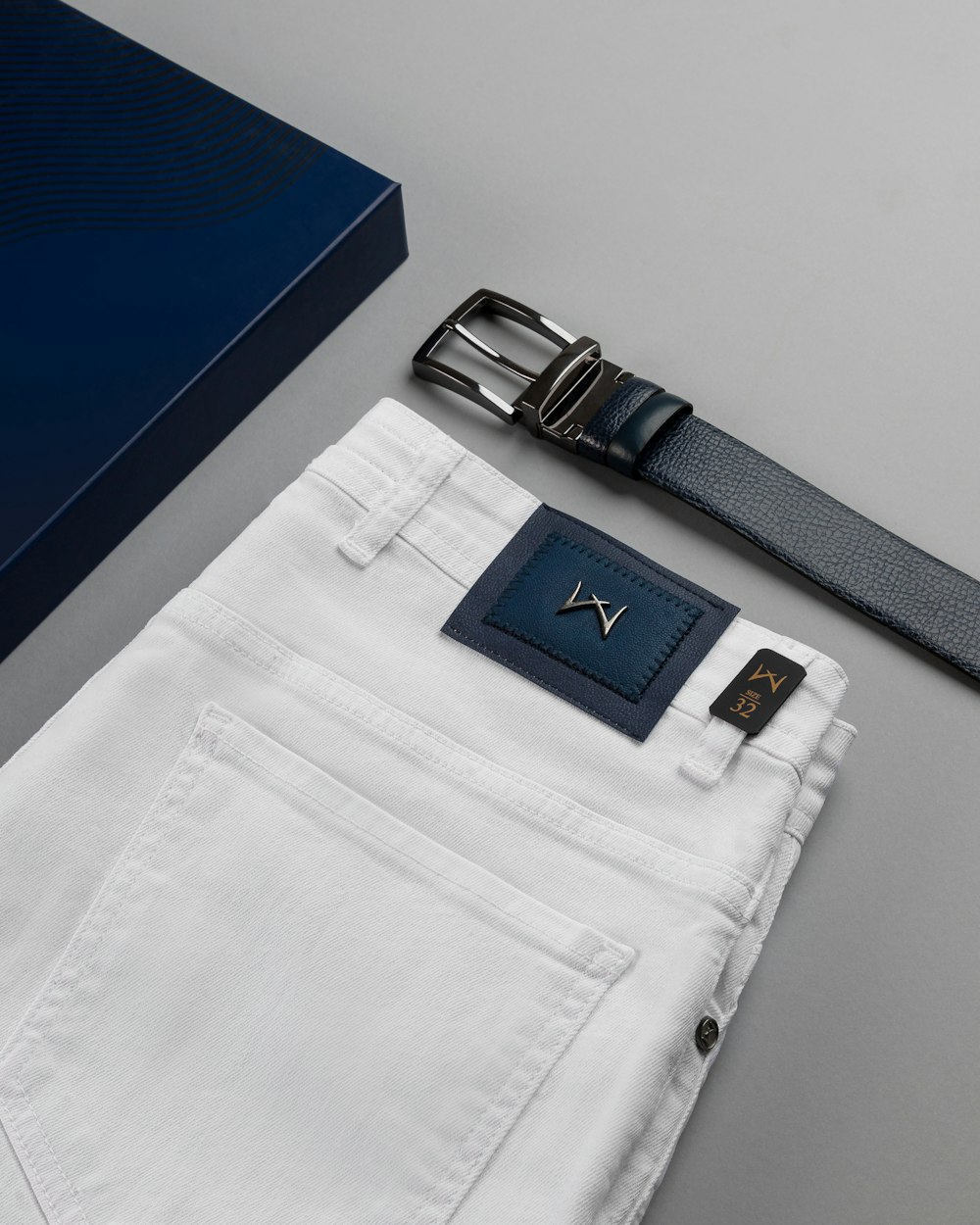 a pair of white jeans with a blue box and a belt