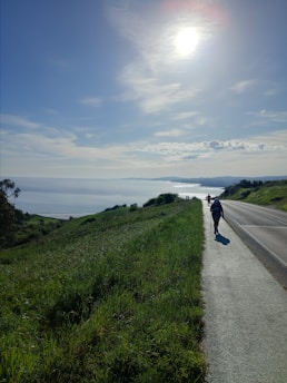 a person riding a motorcycle down a road next to the ocean