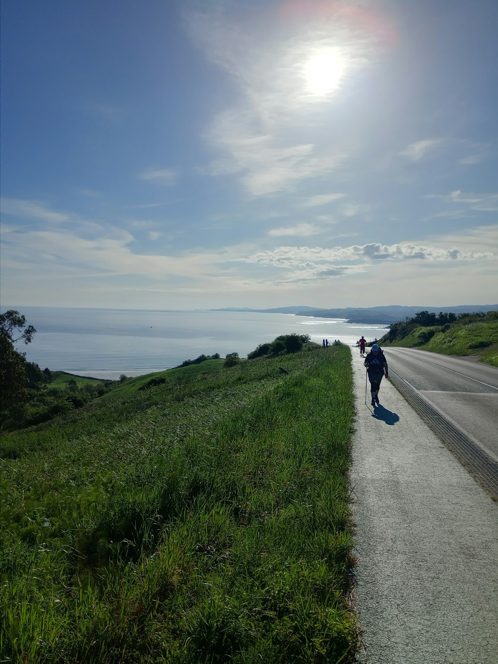 a person riding a motorcycle down a road next to the ocean