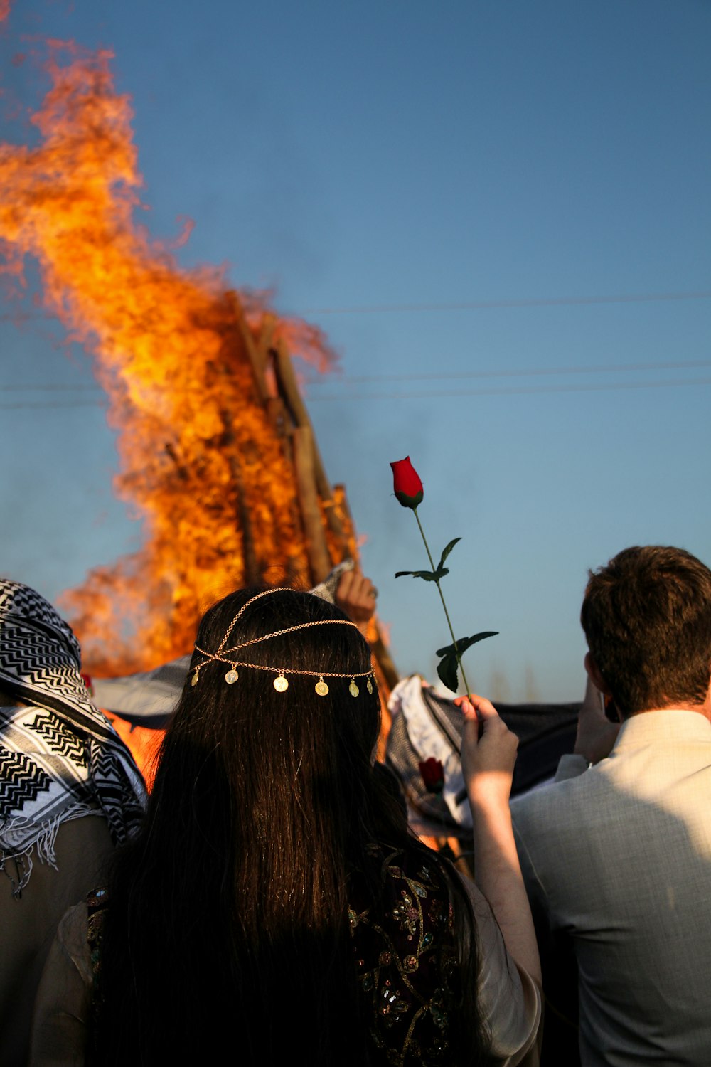 a woman holding a rose in front of a fire