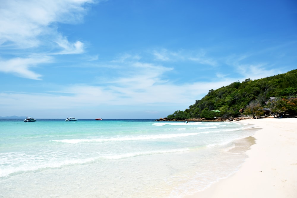 a white sandy beach with boats in the water