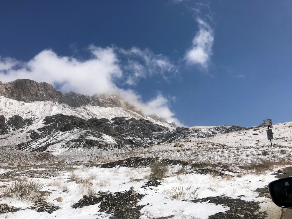 a car driving down a snowy road next to a mountain