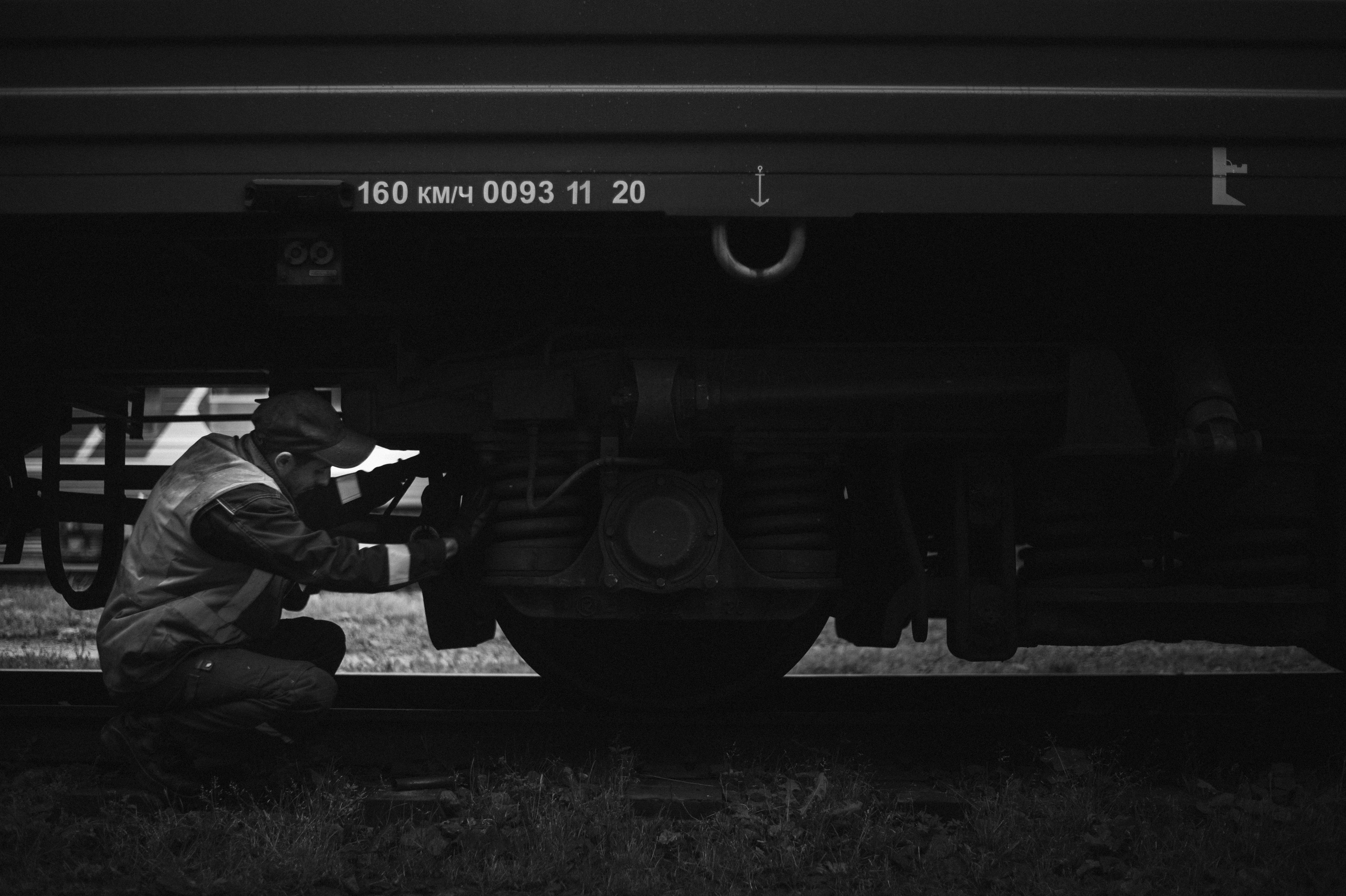 A worker inspects a train car at a train stop.