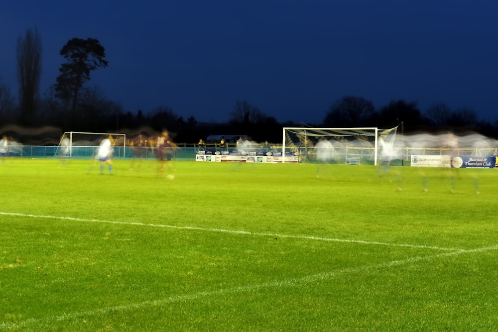 um campo de futebol com jogadores à noite