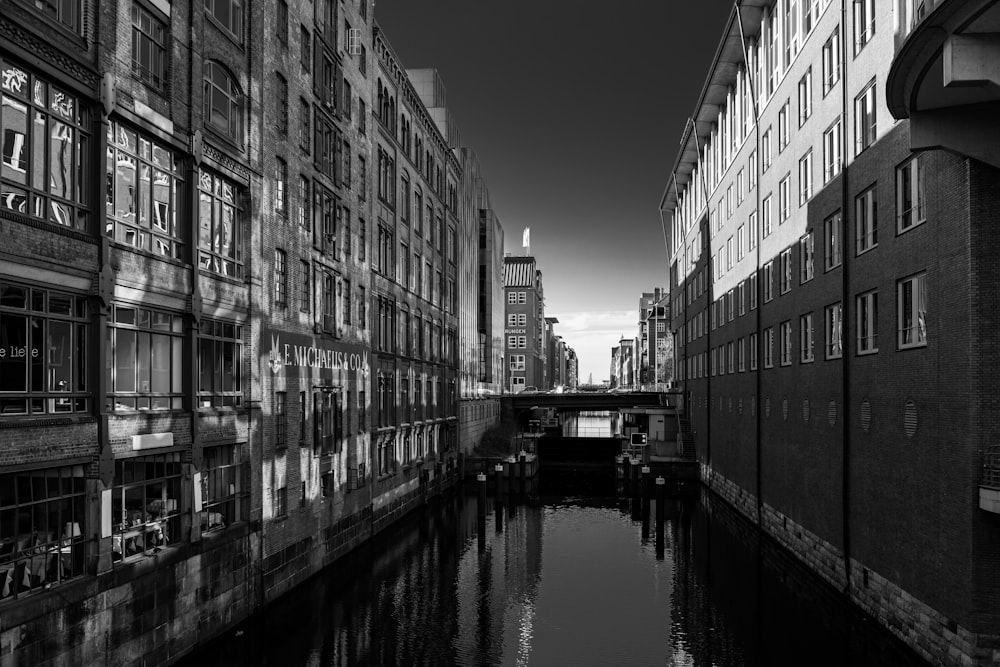 a black and white photo of a canal in a city