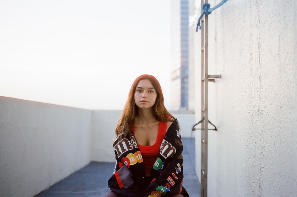 a woman sitting on a ledge with a coat over her shoulders