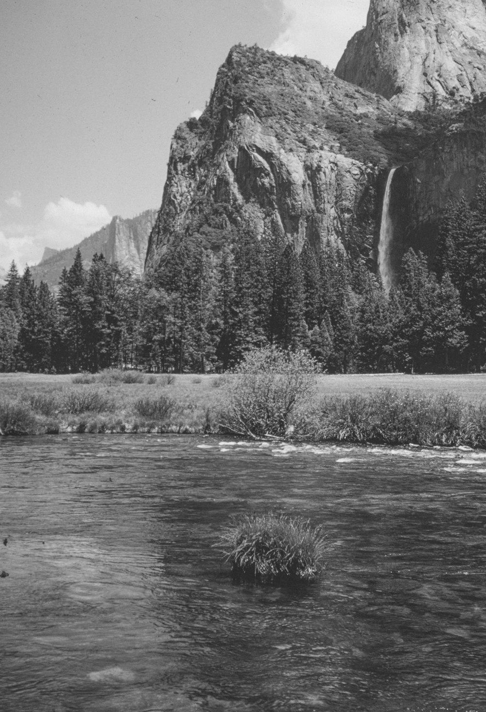 a black and white photo of a mountain and a river