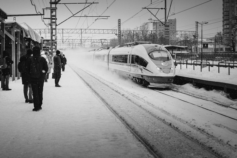 um trem viajando pelos trilhos do trem ao lado de uma plataforma coberta de neve
