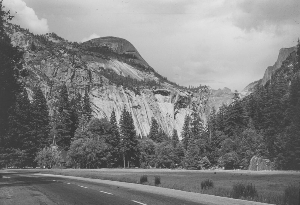 a black and white photo of a road in front of a mountain