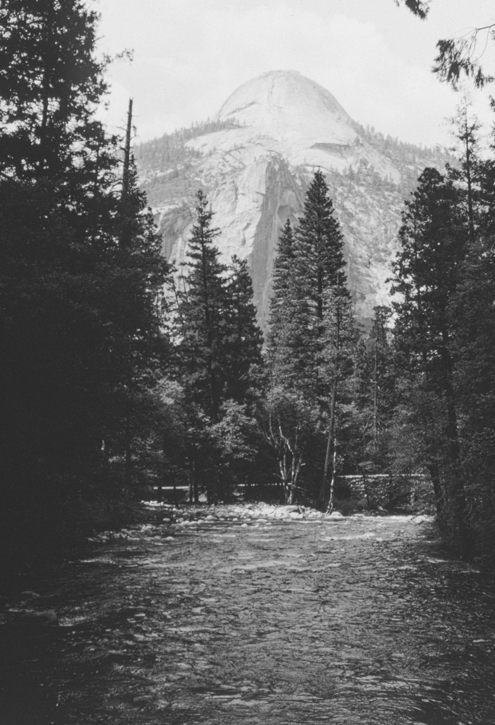 a black and white photo of a mountain and a river