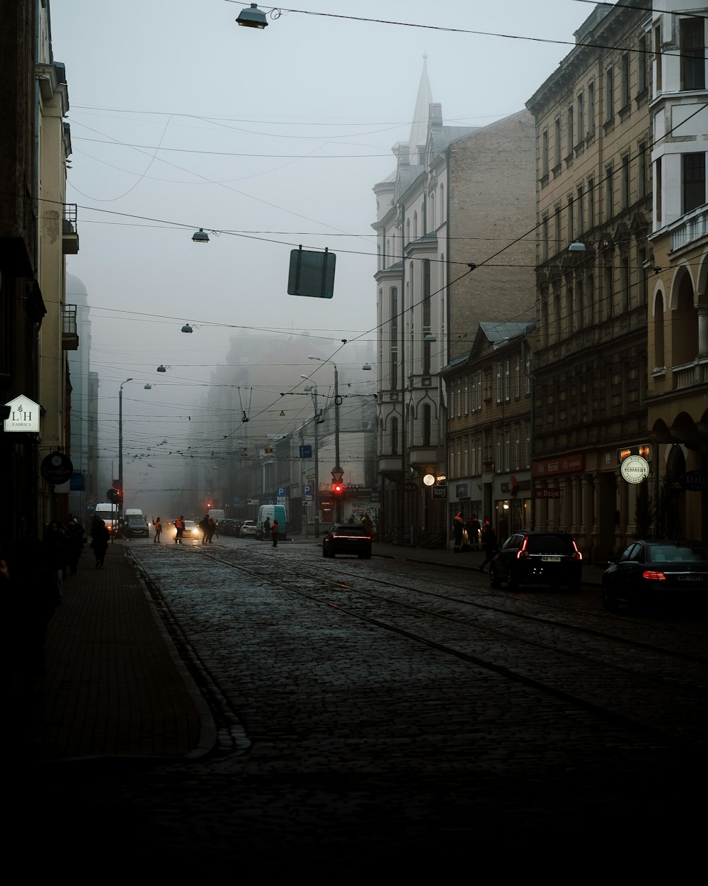 霧のかかった街の通りを車が走り抜ける