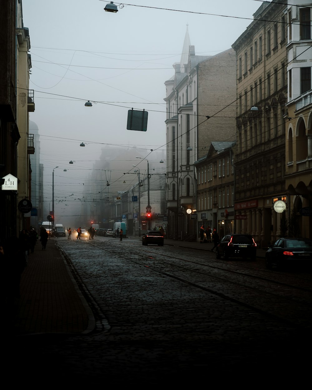 a foggy city street with cars driving down it