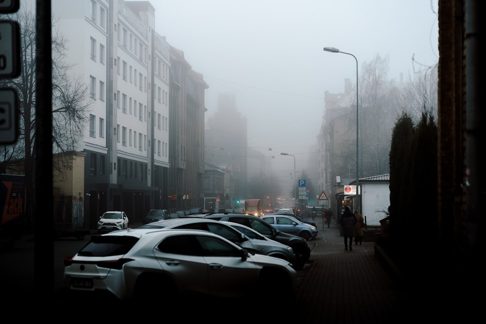 a foggy city street filled with lots of parked cars