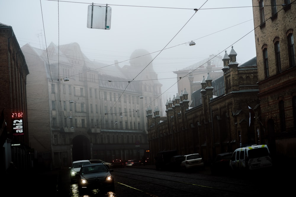 a foggy city street with cars driving down it