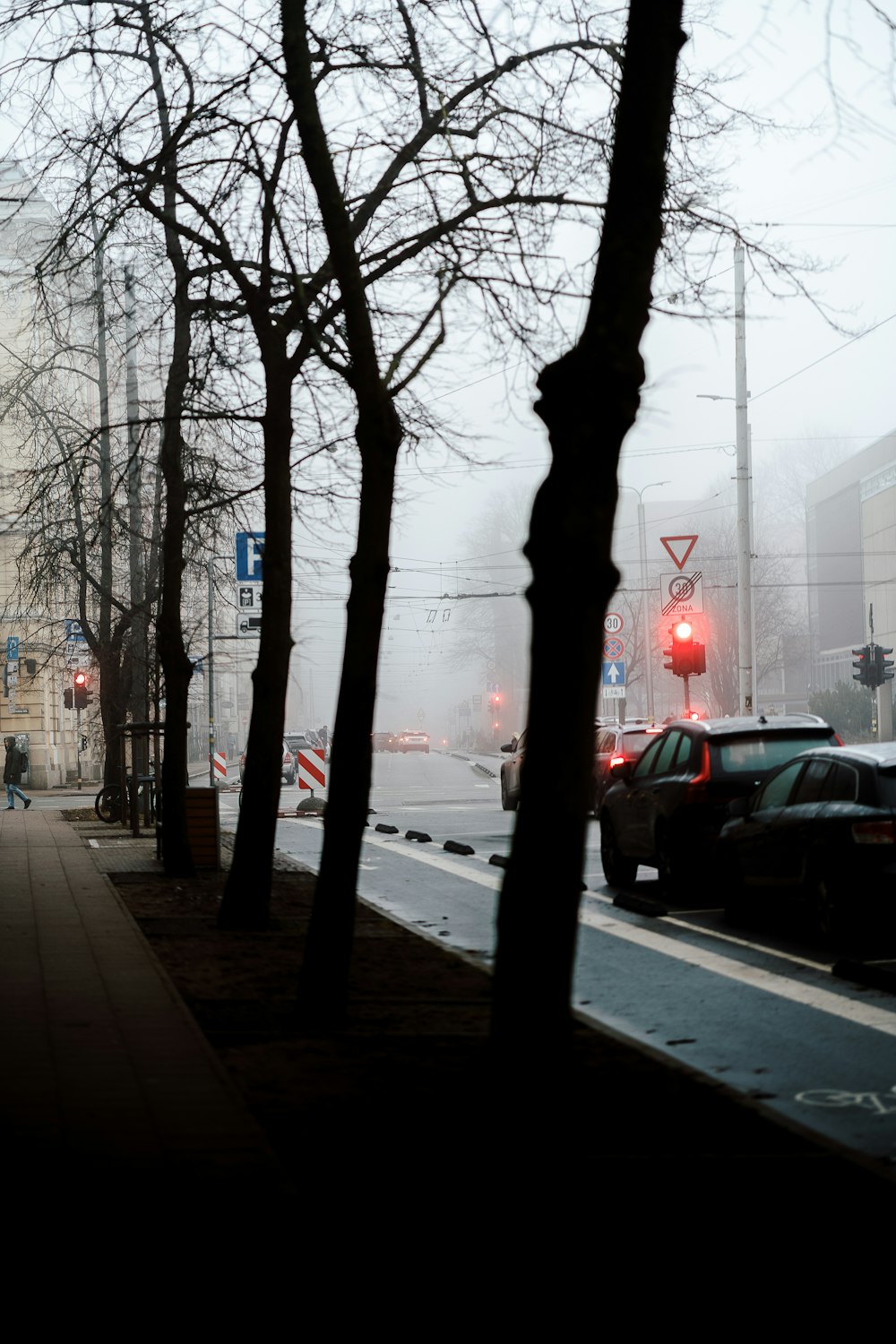 a city street with a red traffic light on a foggy day