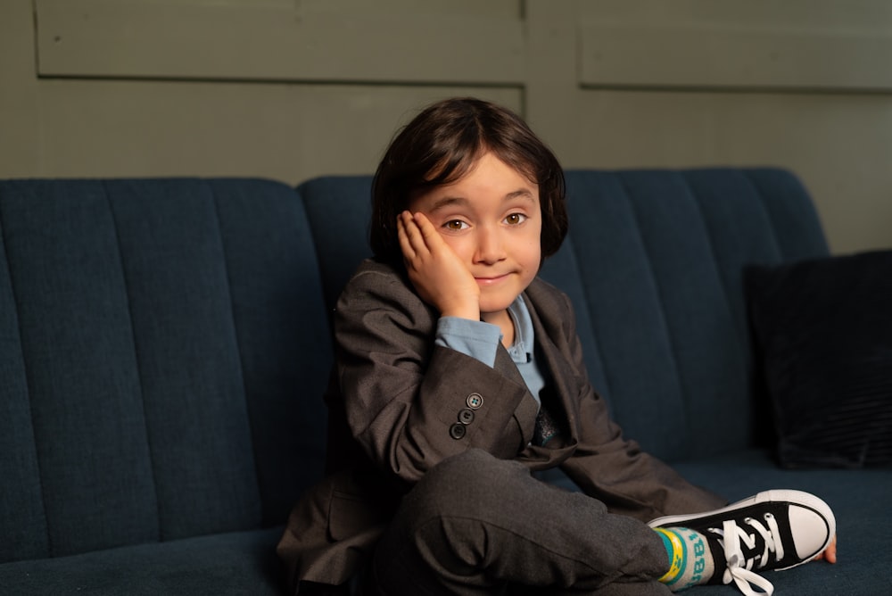 a young boy sitting on a blue couch