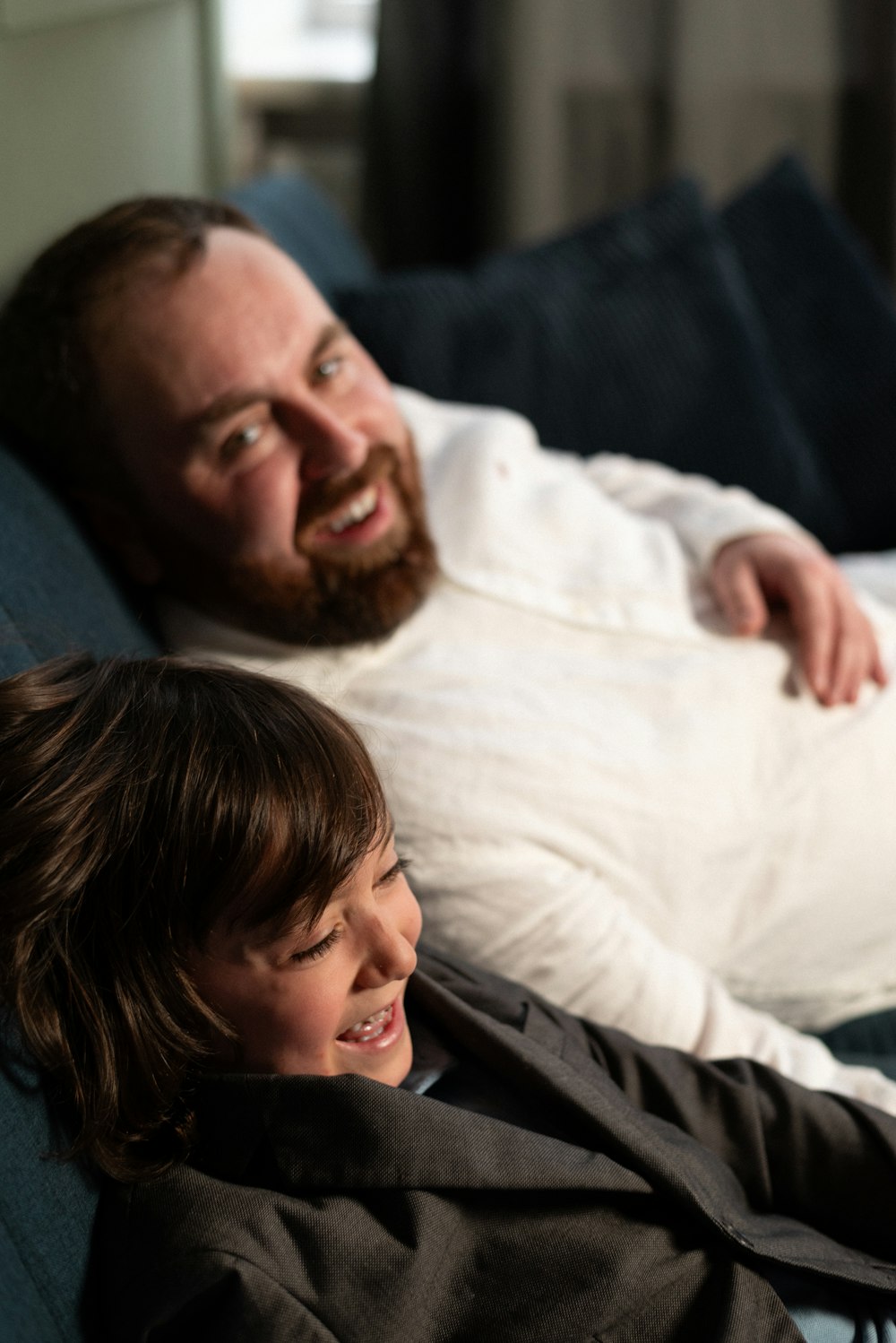 a man laying on a couch next to a little boy