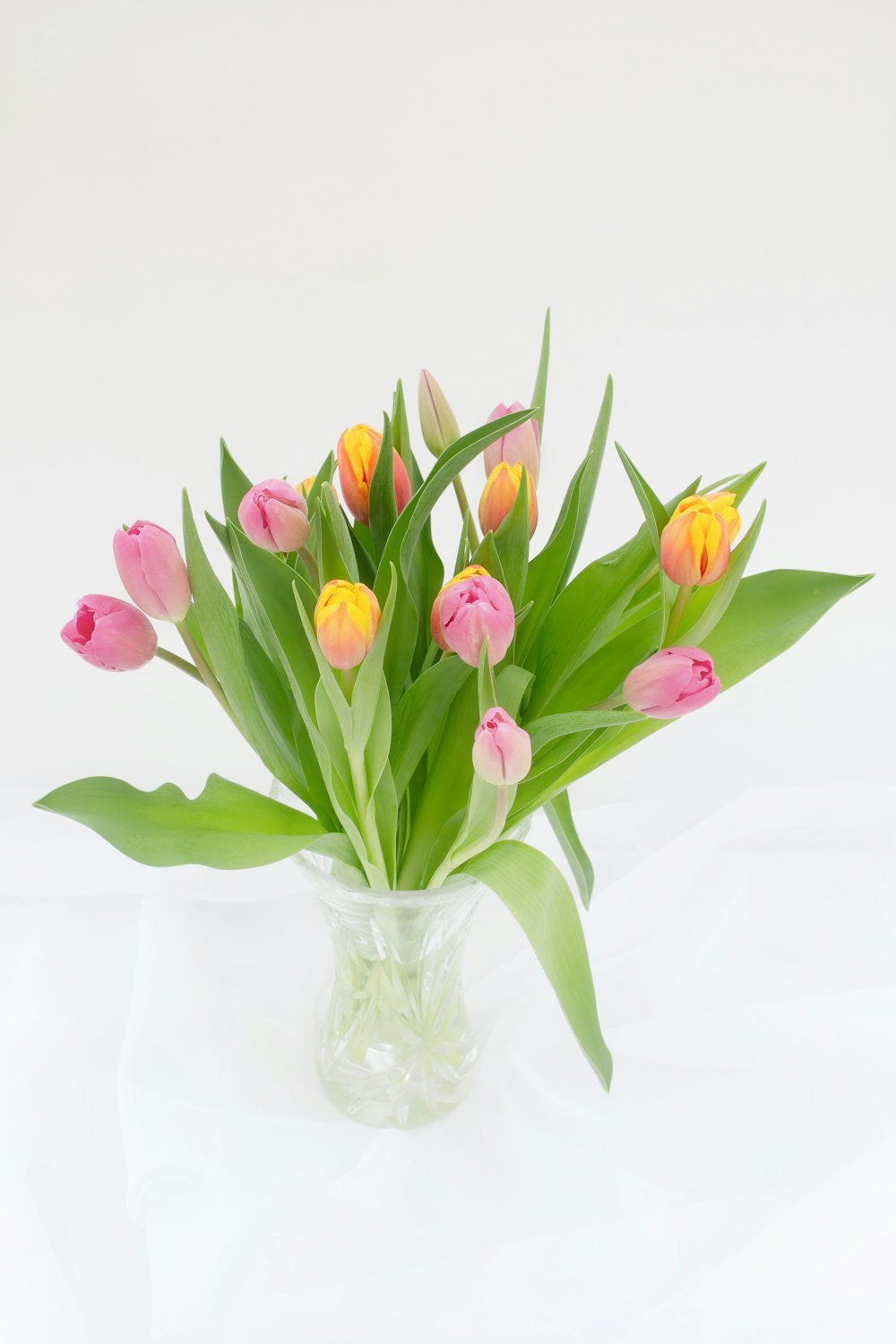 a vase filled with lots of pink and yellow flowers