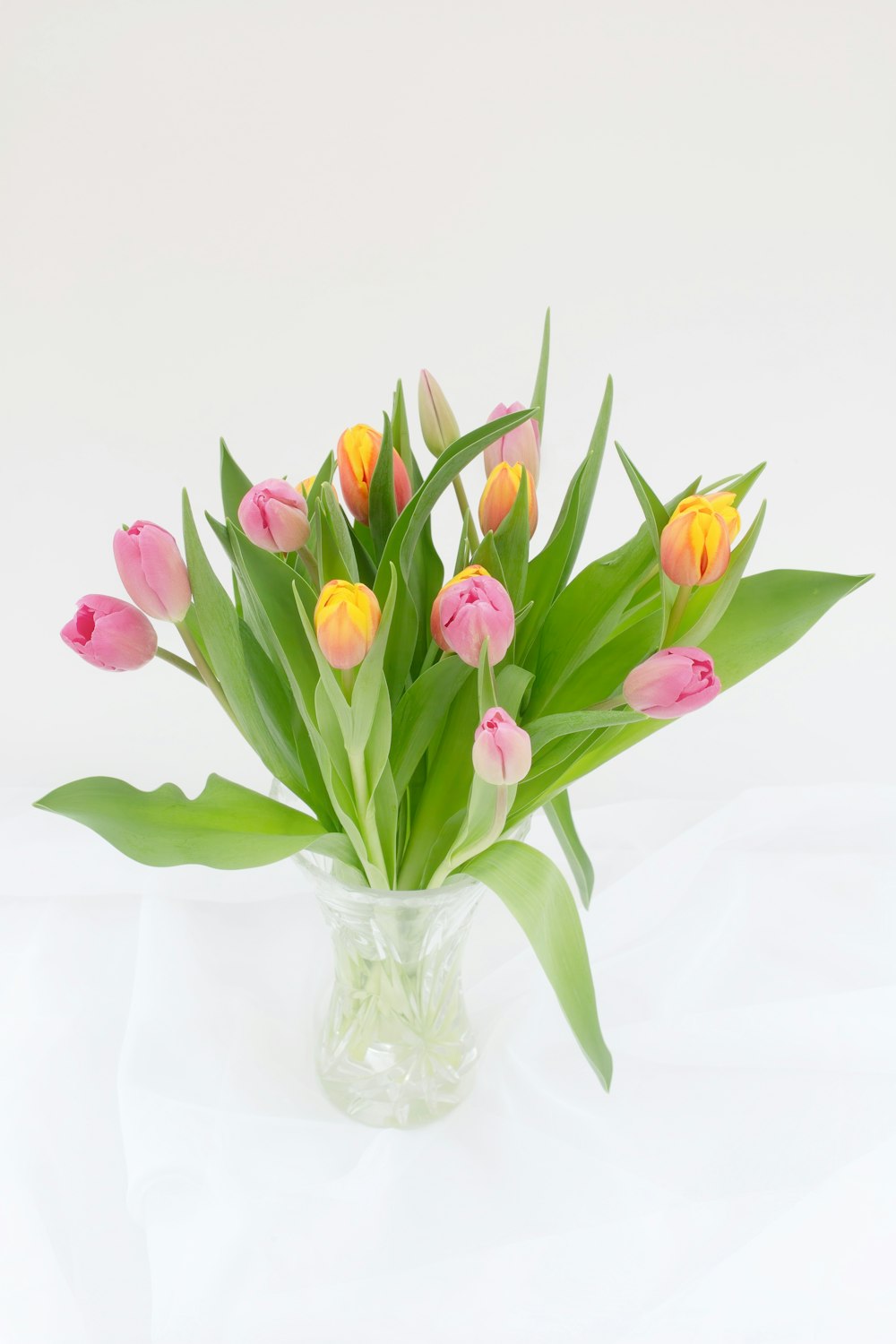 un vase rempli de beaucoup de fleurs roses et jaunes