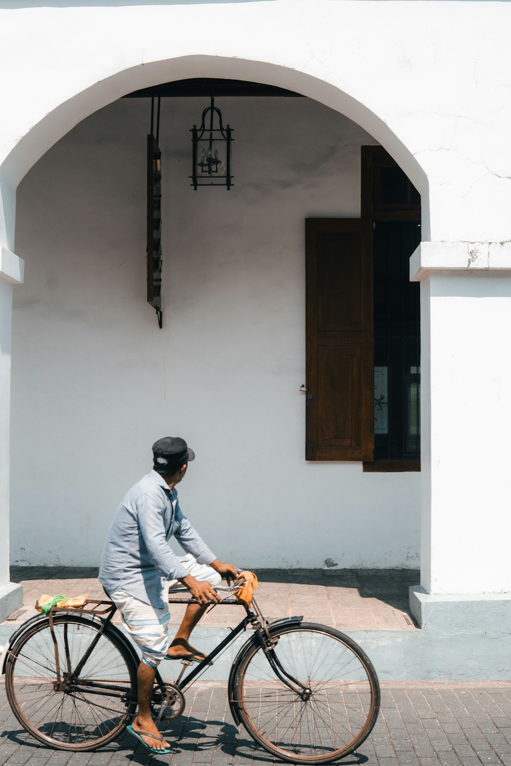 Un hombre andando en bicicleta por una calle junto a un edificio blanco