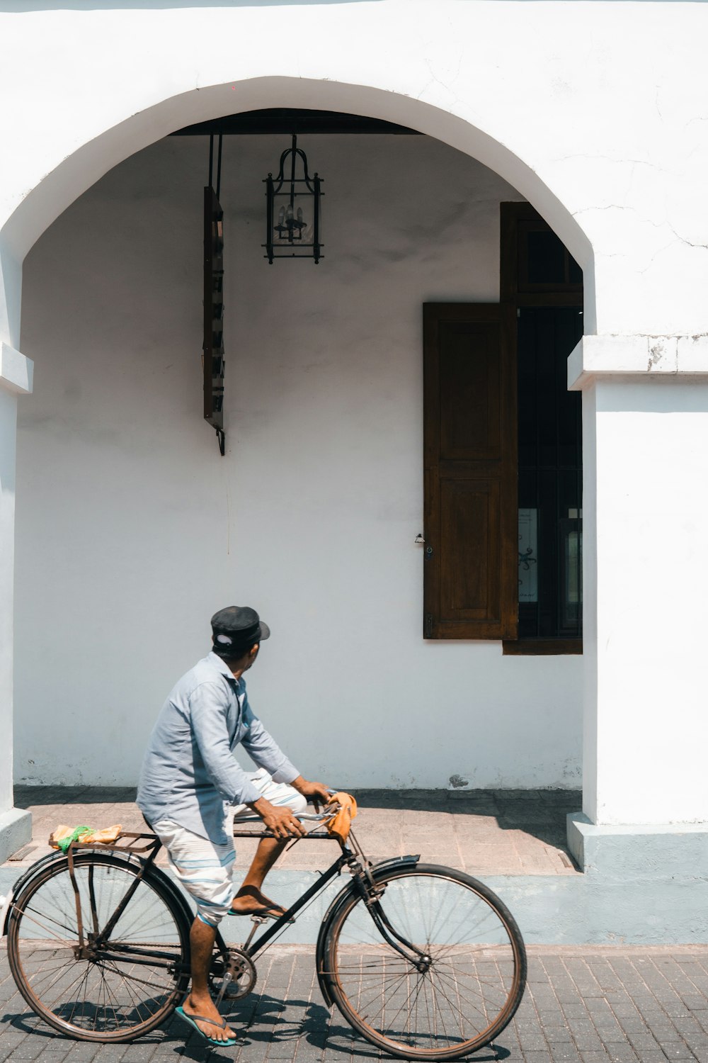 a man riding a bike down a street next to a white building