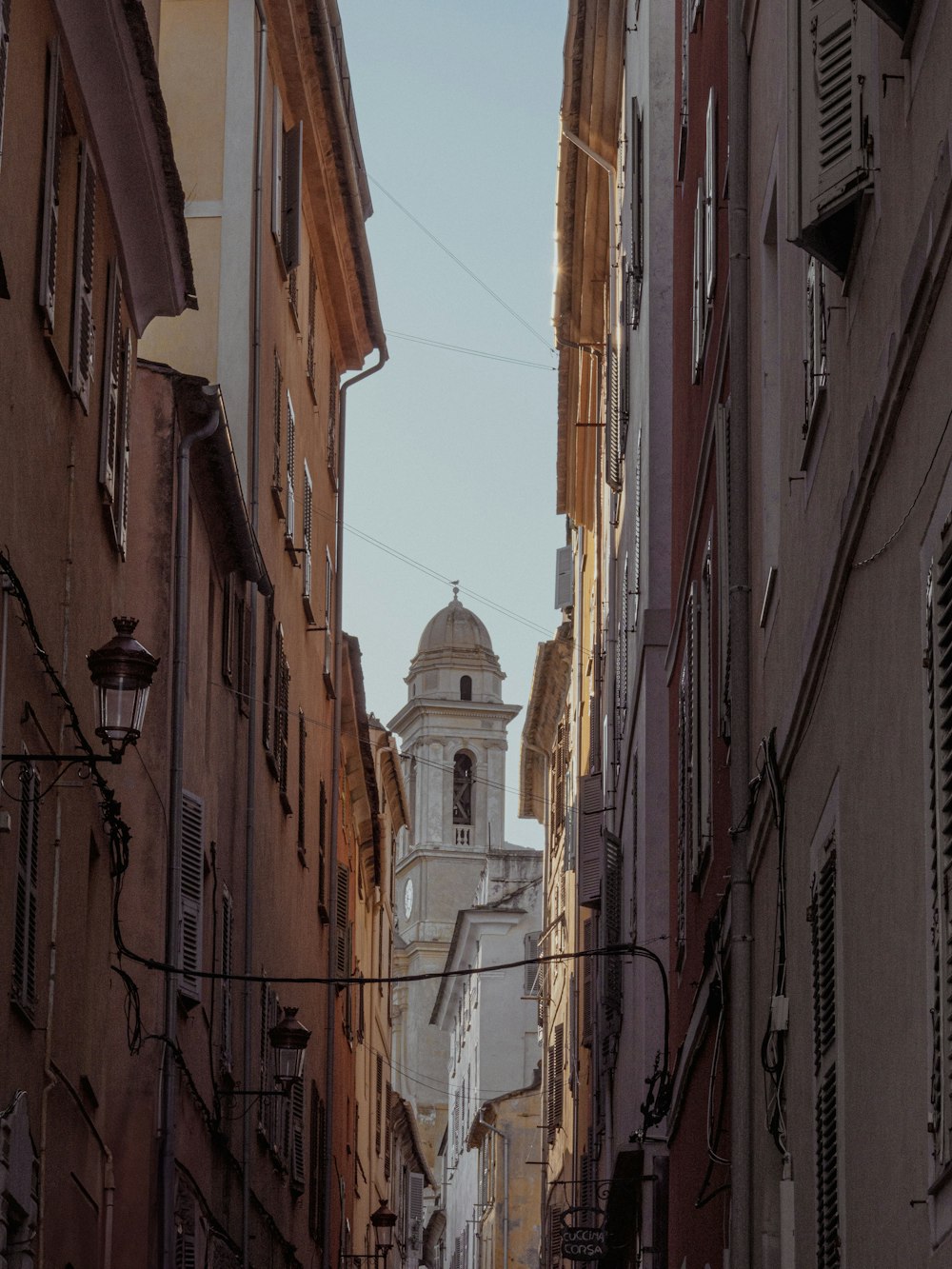 a narrow city street with a church steeple in the background