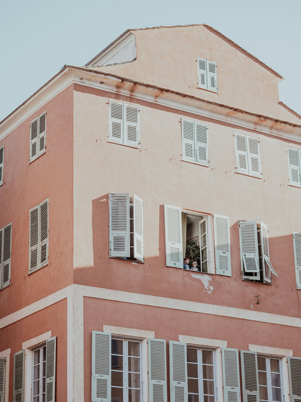 a pink building with white windows and shutters