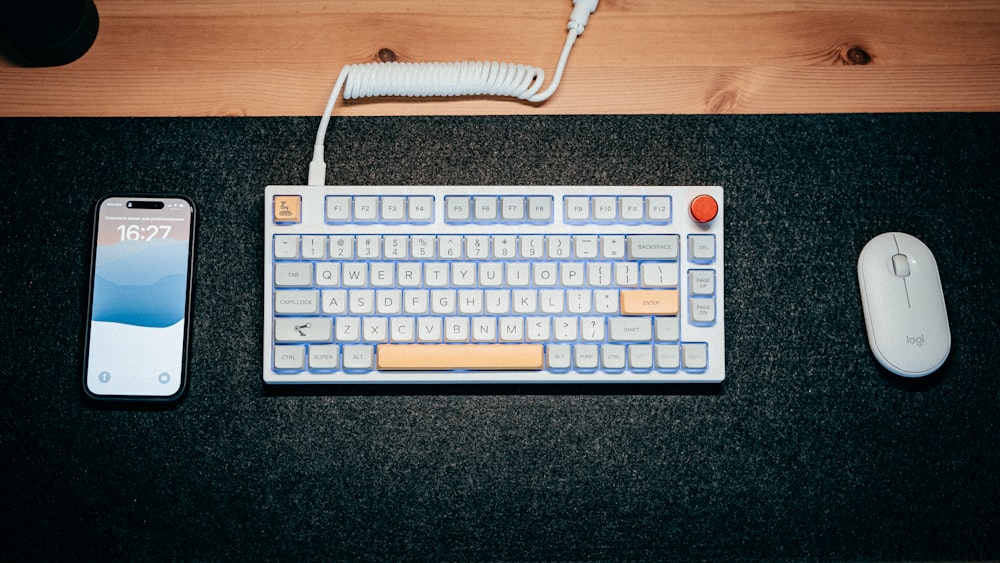 a computer keyboard, mouse, and cell phone on a table