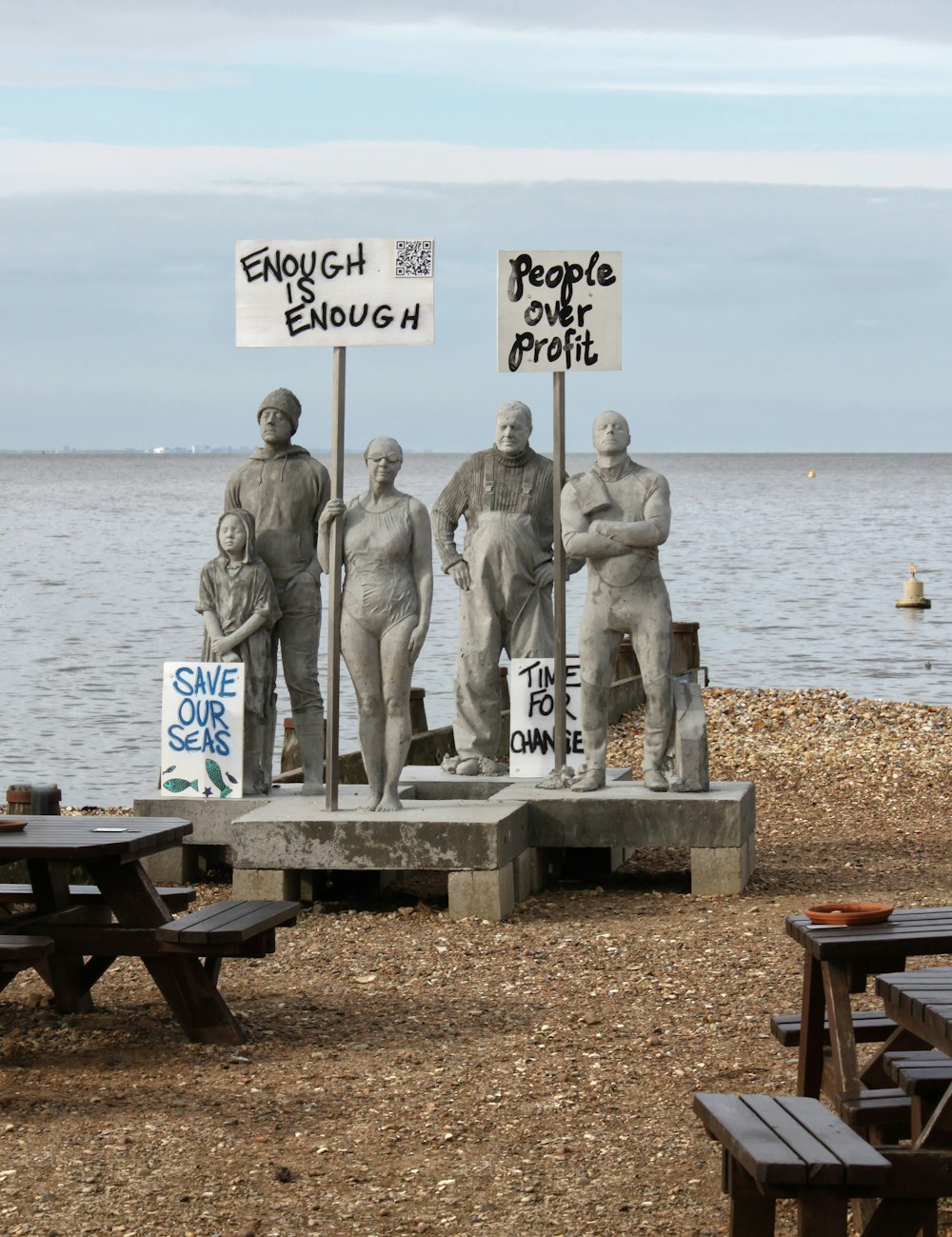 a group of statues sitting on top of a sandy beach