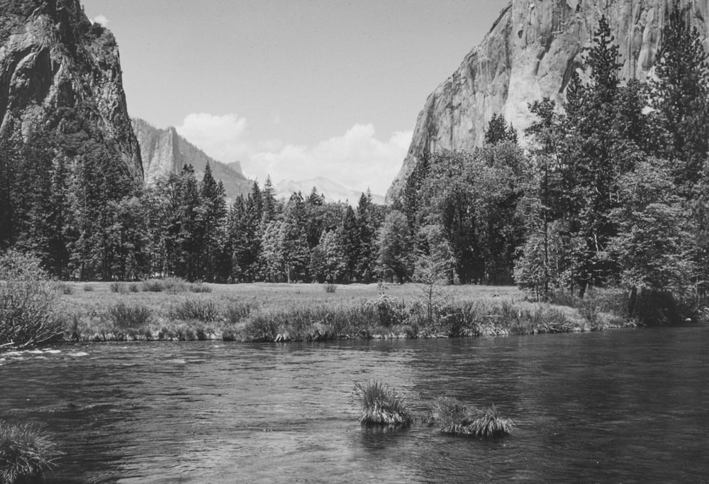 a black and white photo of a river and mountains