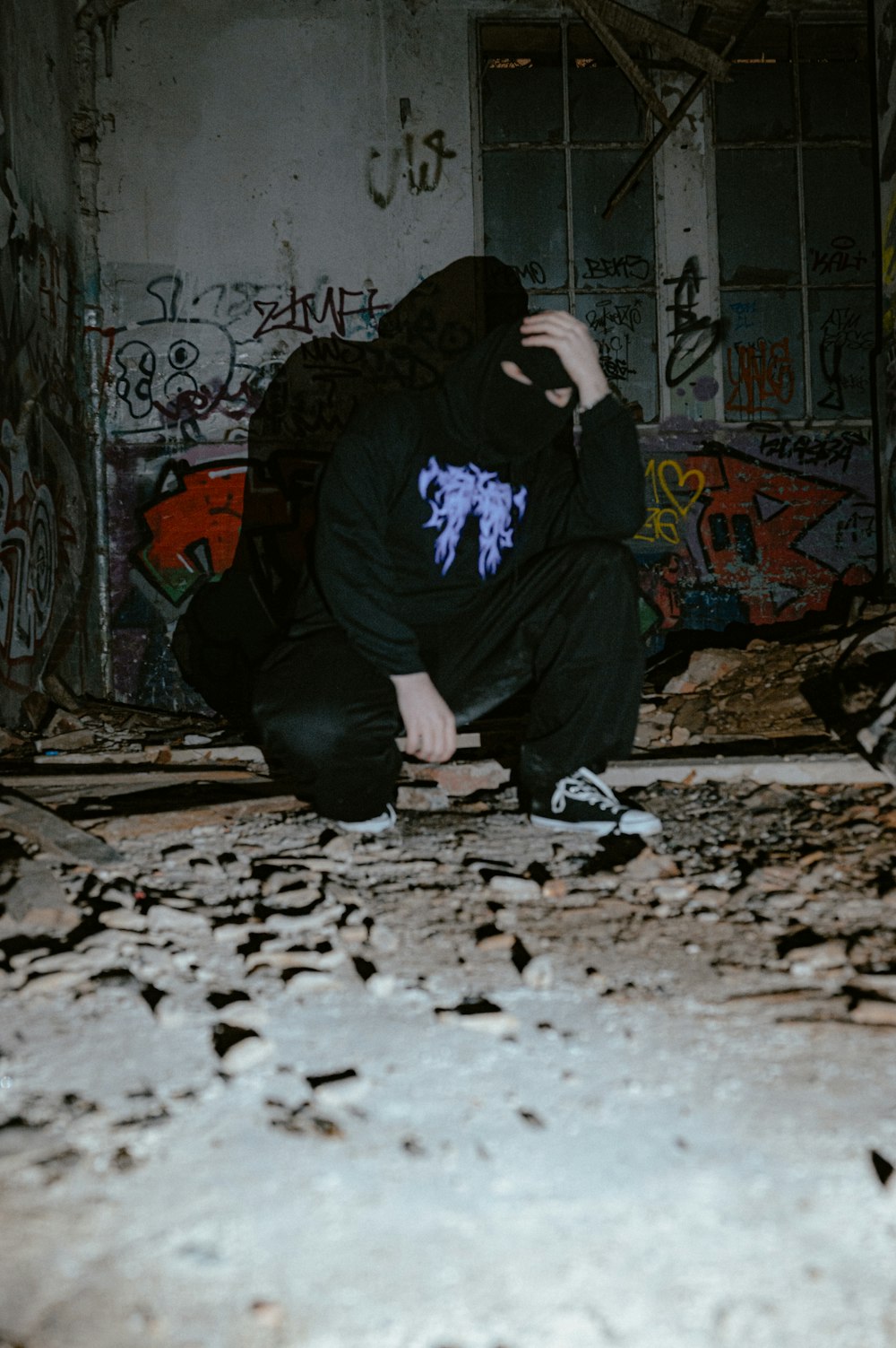 a person kneeling down in a room with graffiti on the walls
