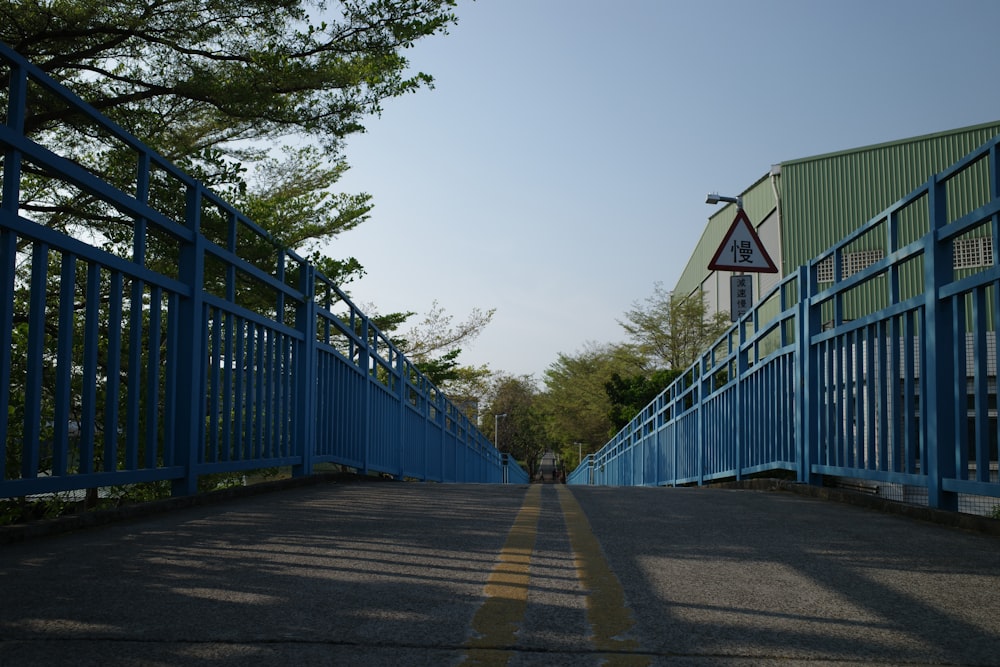 a blue metal bridge over a road next to a building