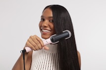 a woman using a hair dryer on her long hair