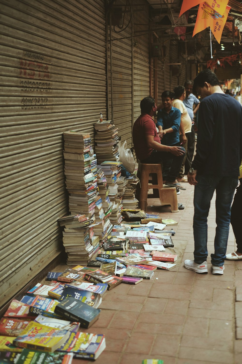 a group of people standing next to a pile of books