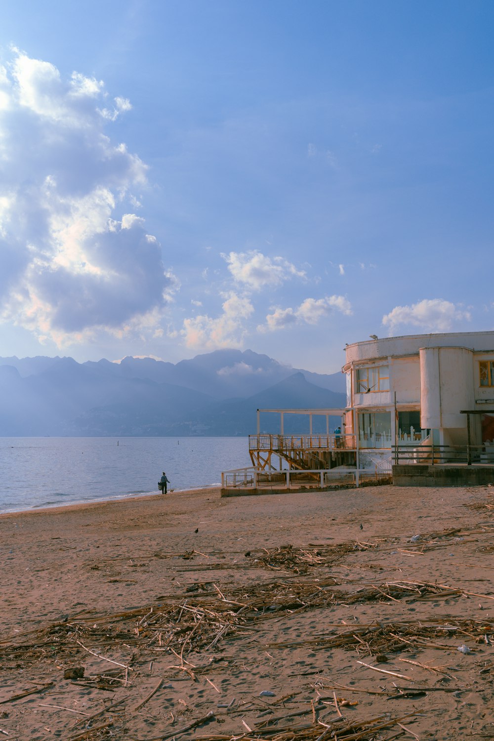 a beach with a house on the shore and mountains in the background