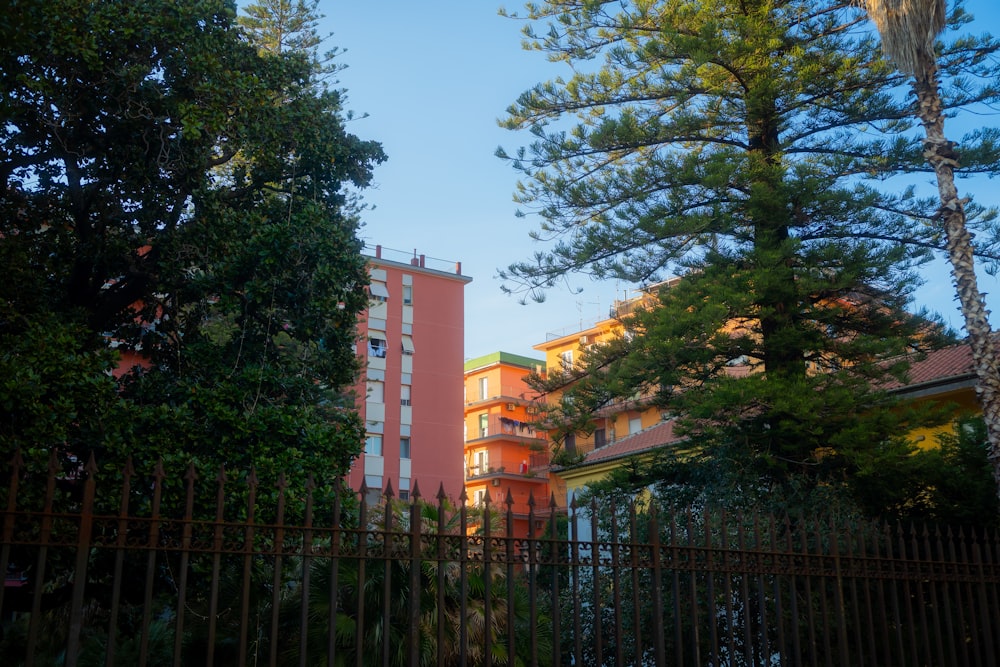 a tall pink building sitting next to a lush green forest