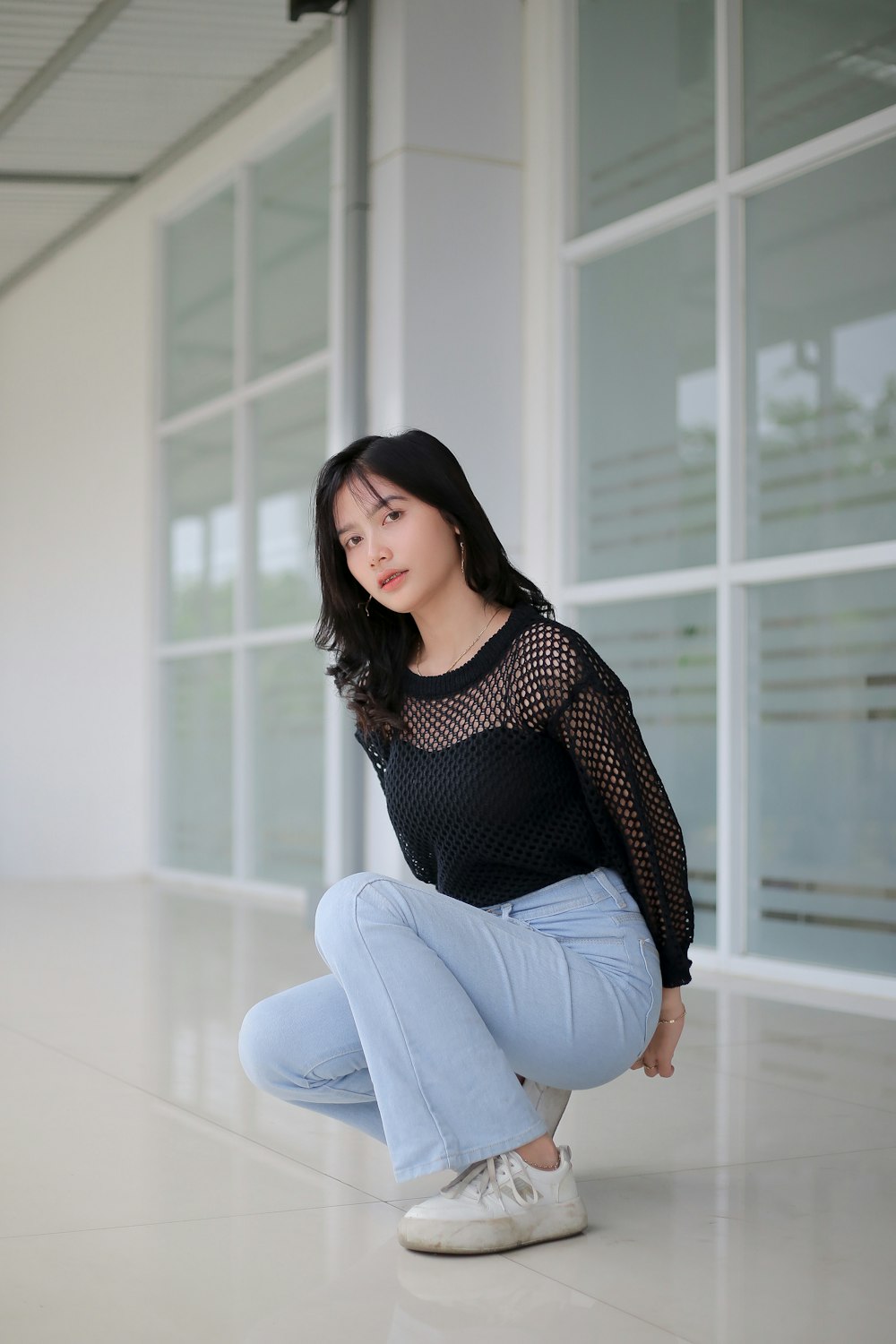 a woman squatting on the floor in front of a building